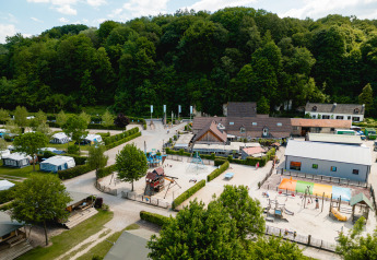 Aerial view of Camping 't Geuldal in Limburg, Netherlands, showing playgrounds, tents, and lush trees.