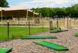 Campo da minigolf con erba sintetica verde e tenda presso Camping 't Geuldal, Limburgo, Paesi Bassi, in estate.