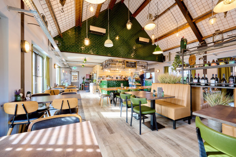 Luminoso y moderno interior de restaurante en Camping 't Geuldal, Limburg, Países Bajos, con decoración verde y madera.