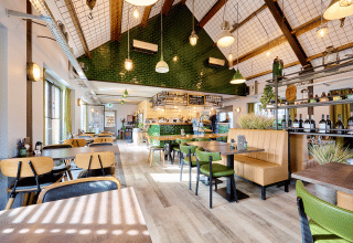 Interno di ristorante moderno e luminoso a Camping 't Geuldal, Limburgo, Paesi Bassi, con arredi verdi e in legno.