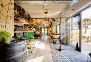 Lyst, moderne restaurantinteriør med grøn bar og træmøbler i Camping 't Geuldal, Limburg, Holland.