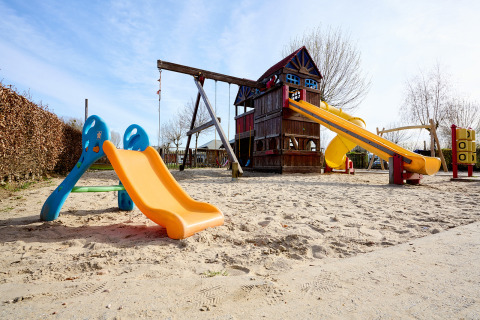 Parque infantil en Camping 't Geuldal, Limburgo, Países Bajos, con toboganes y estructura sobre arena.