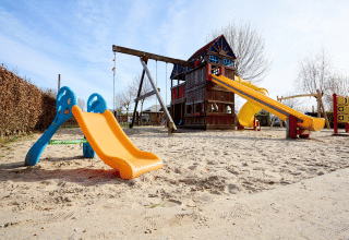 Aire de jeux au Camping 't Geuldal, Limbourg, Pays-Bas, avec toboggans et structure d’escalade sur sable.