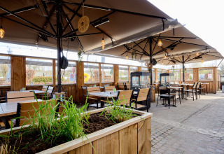 Outdoor dining area at Camping 't Geuldal in Limburg, Netherlands, with wooden tables and large umbrellas