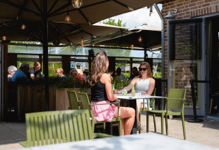 Deux femmes prennent un verre à la terrasse de Camping 't Geuldal, parc de vacances à Limbourg, Pays-Bas.
