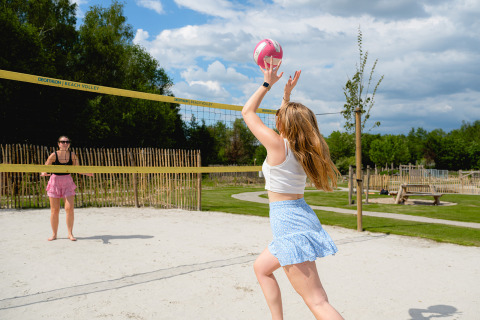 Twee vrouwen spelen volleybal op het zand bij Camping 't Geuldal, een vakantiepark in Limburg, Nederland.
