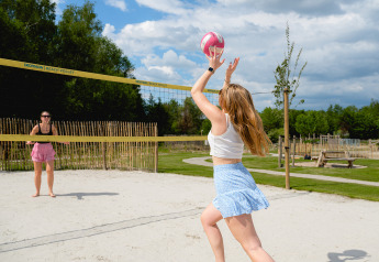 Two women play beach volleyball in the sun at Camping 't Geuldal holiday park in Limburg, Netherlands.