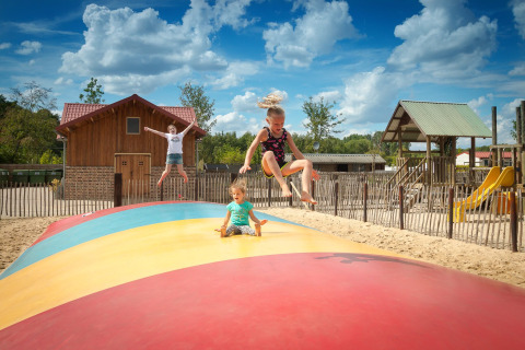 Kinder springen und spielen auf einem großen bunten Luftkissen auf Camping 't Geuldal in Limburg, Niederlande.