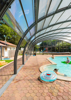 Piscina cubierta con familias nadando y relajándose en Camping Au Clos de La Chaume, Grand Est, Francia.