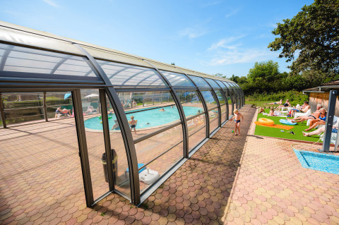 Piscina coperta e ospiti che prendono il sole al Camping Au Clos de La Chaume nel Grand Est, Francia.