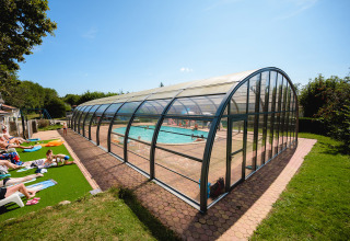 Piscina cubierta con huéspedes tomando el sol en Camping Au Clos de La Chaume, Grand Est, Francia.