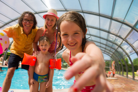 Famiglia felice si diverte nella piscina coperta di Camping Au Clos de La Chaume, nel Grand Est, Francia.