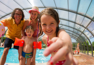 Famiglia felice si diverte nella piscina coperta di Camping Au Clos de La Chaume, nel Grand Est, Francia.