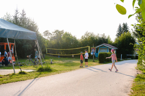 Des enfants jouent dehors près d’un terrain de volley dans un parc de vacances à Grand Est, France, par une journée ensoleillée.