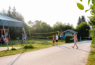 Children playing outdoors near a volleyball court at a holiday park in Grand Est, France, on a sunny day.