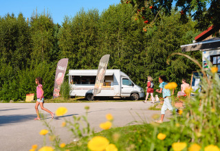 Kinderen en volwassenen genieten van de zon bij een foodtruck op Camping Au Clos de La Chaume in Frankrijk.