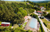 Luftfoto af Camping Au Clos de La Chaume med overdækket pool, grønne træer og bygninger i Grand Est, Frankrig.