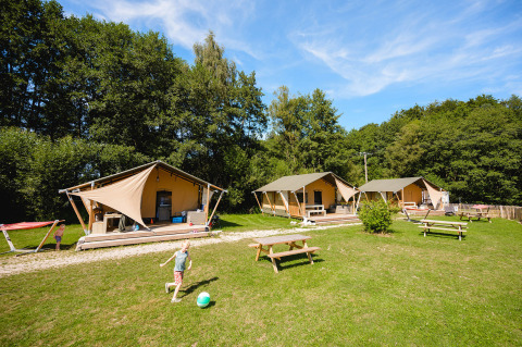 Bambini giocano con un pallone davanti alle tende glamping al Camping Au Clos de La Chaume, Grand Est, Francia.