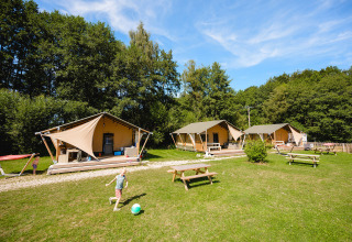 Bambini giocano con un pallone davanti alle tende glamping al Camping Au Clos de La Chaume, Grand Est, Francia.