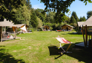 Tende e amache a Camping Au Clos de La Chaume tra il verde del parco vacanze in Grand Est, Francia.
