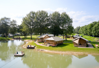 Lodgetenten aan het water en mensen die genieten bij Camping Betuwe vakantiepark in Gelderland, Nederland.