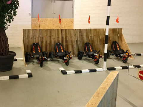 Cuatro karts de pedales con diseños de llamas estacionados en una pista cubierta de Camping Betuwe, Gelderland.