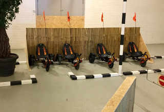Fire pedal-gokarts med flammemønstre holder parkeret ved et indendørs spor i Camping Betuwe, Gelderland.