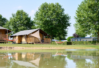 Tentes glamping et mobile home au bord d’un étang au Camping Betuwe, parc de vacances en Gueldre, Pays-Bas.