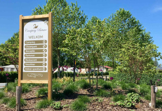 Ingangsbord van Camping Betuwe vakantiepark in Gelderland, Nederland, omgeven door bomen en struiken.