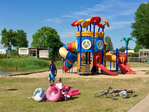 Niños juegan en un colorido parque infantil en Camping Betuwe, parque vacacional de Gelderland, Países Bajos.