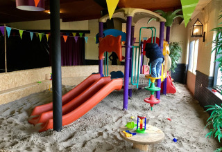 Binnen speeltuin met zand, klimtoestellen en glijbanen bij Camping Betuwe in Gelderland, Nederland.