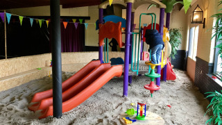 Parque infantil interior con toboganes, arena y niño jugando en Camping Betuwe, Gelderland, Países Bajos.