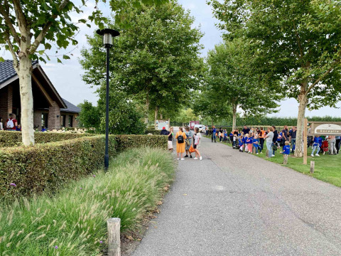 Famiglie e bambini si radunano vicino al sentiero e alla reception del Camping Betuwe in Gelderland.