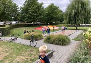 Kinderen spelen op een speelplein met springkussen en fietsen bij Camping Betuwe, Gelderland, Nederland.