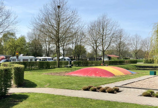 Speelplein met kleurrijk springkussen op Camping Betuwe in Gelderland, Nederland, met caravans.