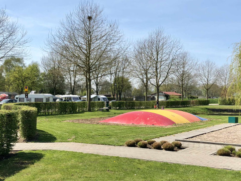 Parque infantil con cojín de salto colorido en Camping Betuwe, Gelderland, Países Bajos, entre caravanas.