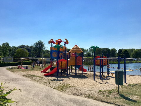 Parque infantil y lago en Camping Betuwe, un parque de vacaciones en Gelderland, Países Bajos, en día soleado.