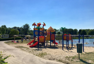 Parque infantil y lago en Camping Betuwe, un parque de vacaciones en Gelderland, Países Bajos, en día soleado.