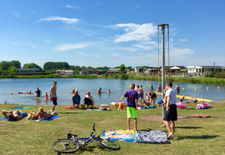 Gezinnen ontspannen aan het meer op Camping Betuwe, een vakantiepark in Gelderland, Nederland, met zon.