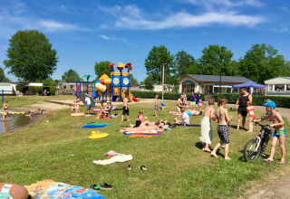 Familles et enfants profitent du soleil et des jeux près du lac au Camping Betuwe, Gelderland, Pays-Bas.