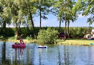 Kinderen spelen op opblaasbare boten in een vijver bij Camping Betuwe, een vakantiepark in Gelderland, Nederland.