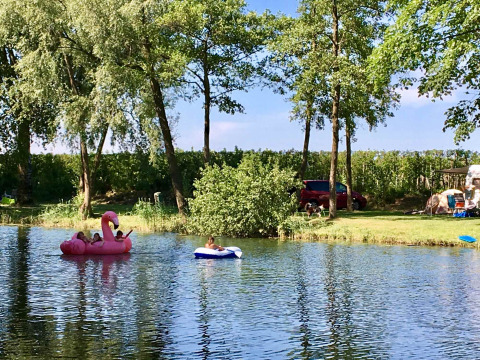 Children playing on inflatable rafts in a lake at Camping Betuwe, a holiday park in Gelderland, Netherlands.