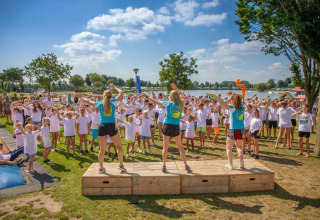 Kinderen en volwassenen nemen deel aan groepsactiviteiten bij Camping Betuwestrand in Gelderland, Nederland.