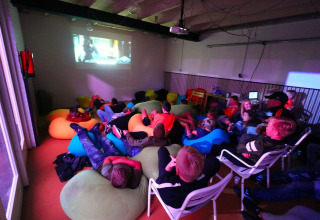 Kinderen kijken naar een film op zitzakken in een zaal van Camping Betuwestrand, Gelderland, Nederland.