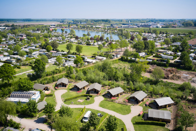 Luchtfoto van vakantiepark Camping Betuwestrand met huisjes, groen en meer in Gelderland, Nederland.