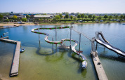 Parco acquatico con scivoli curvi sopra un lago al Camping Betuwestrand, parco vacanze in Gelderland, Olanda.