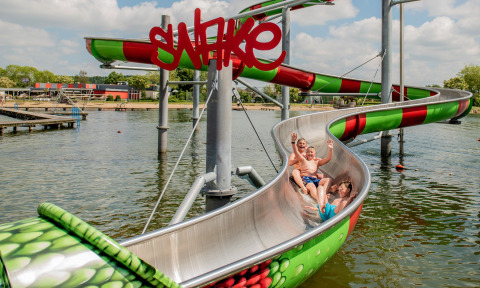 Niños disfrutan de un tobogán acuático colorido sobre el lago en Camping Betuwestrand, Gelderland, Países Bajos.