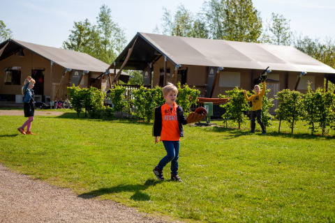 Niños juegan en el césped frente a tiendas en Camping Betuwestrand, un parque vacacional en Gelderland, Países Bajos.