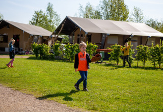 Children play on the grass outside tents at Camping Betuwestrand holiday park in Gelderland, Netherlands.
