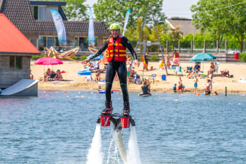 Una persona con traje de neopreno y chaleco salvavidas hace flyboard en Camping Betuwestrand, Países Bajos.